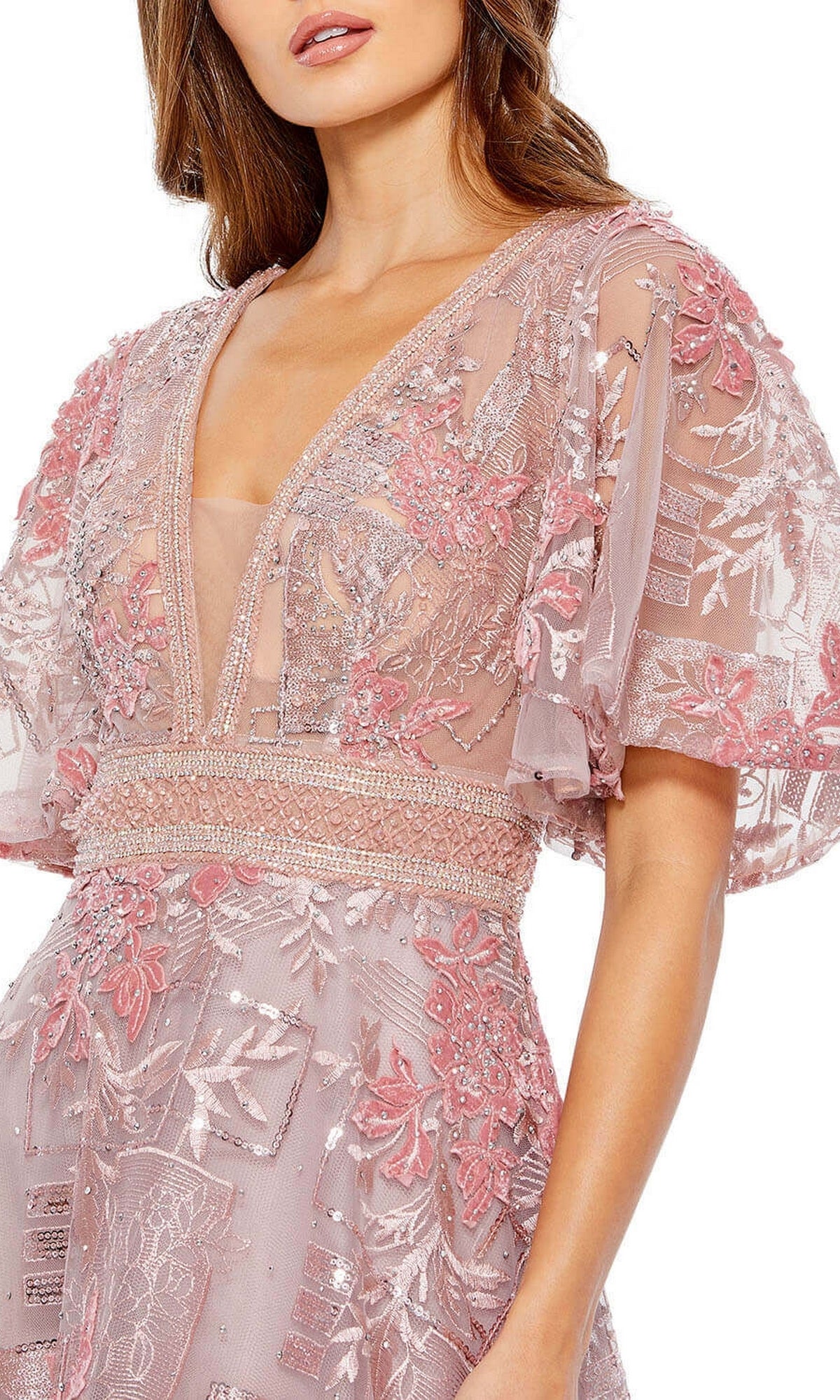 A woman wears the Long Formal Dress 20262 by Mac Duggal, a light pink A-line gown with sheer flounce sleeves, deep V neckline, and intricate floral and geometric embroidery.